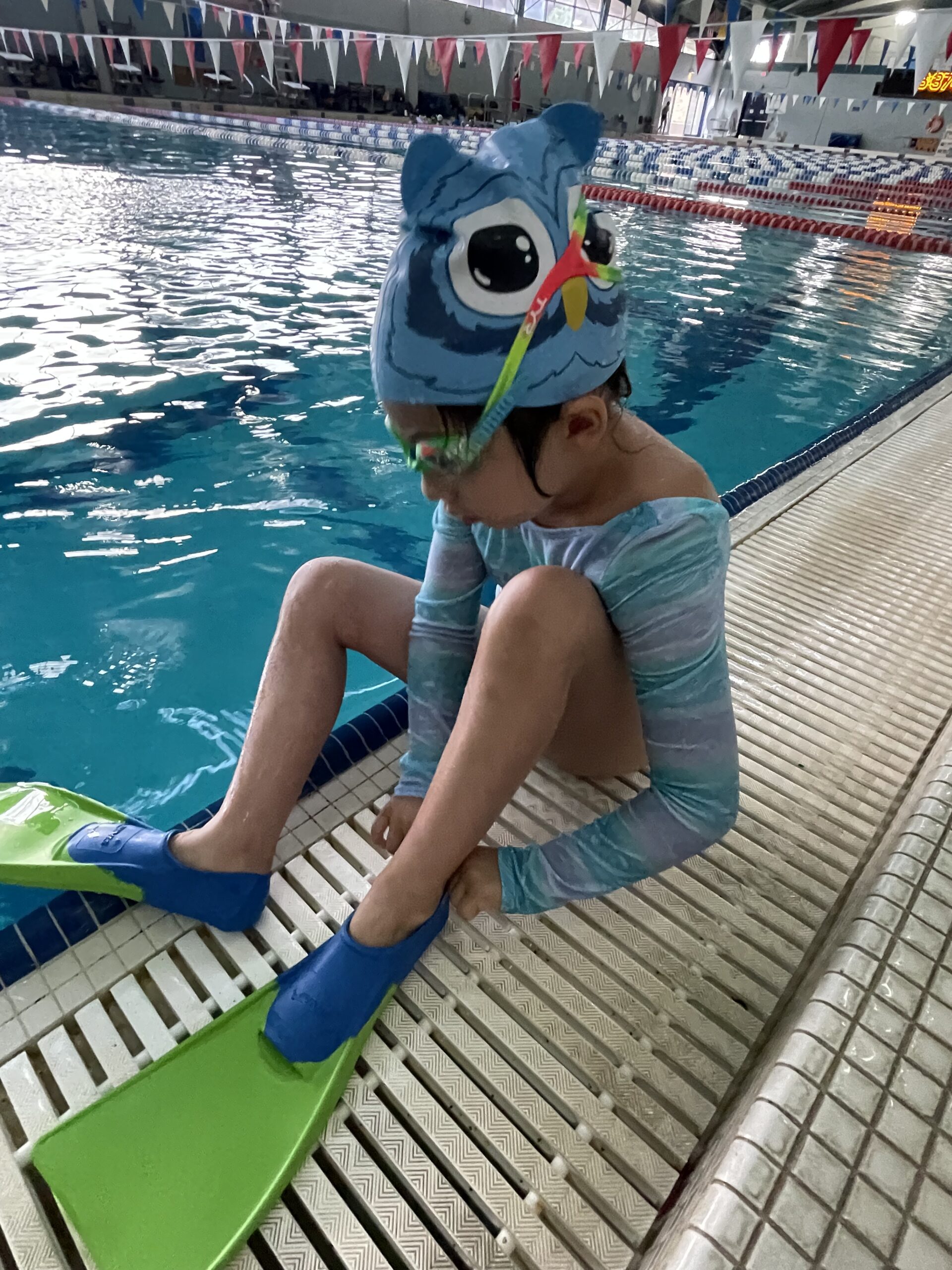 Young girl at pool putting flippers on