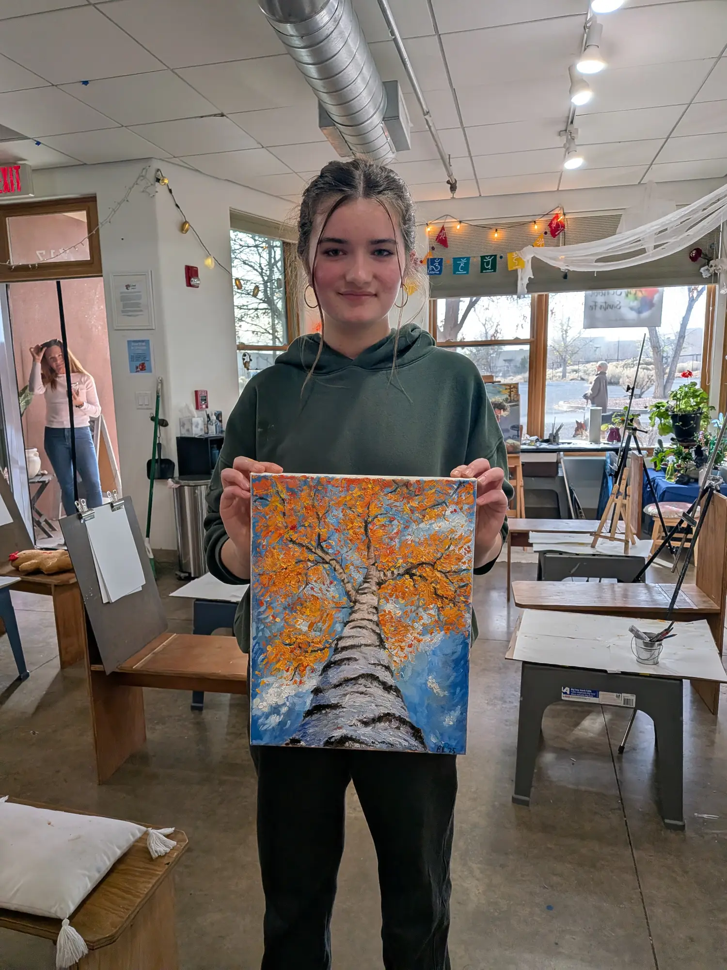 student displaying painting of tree