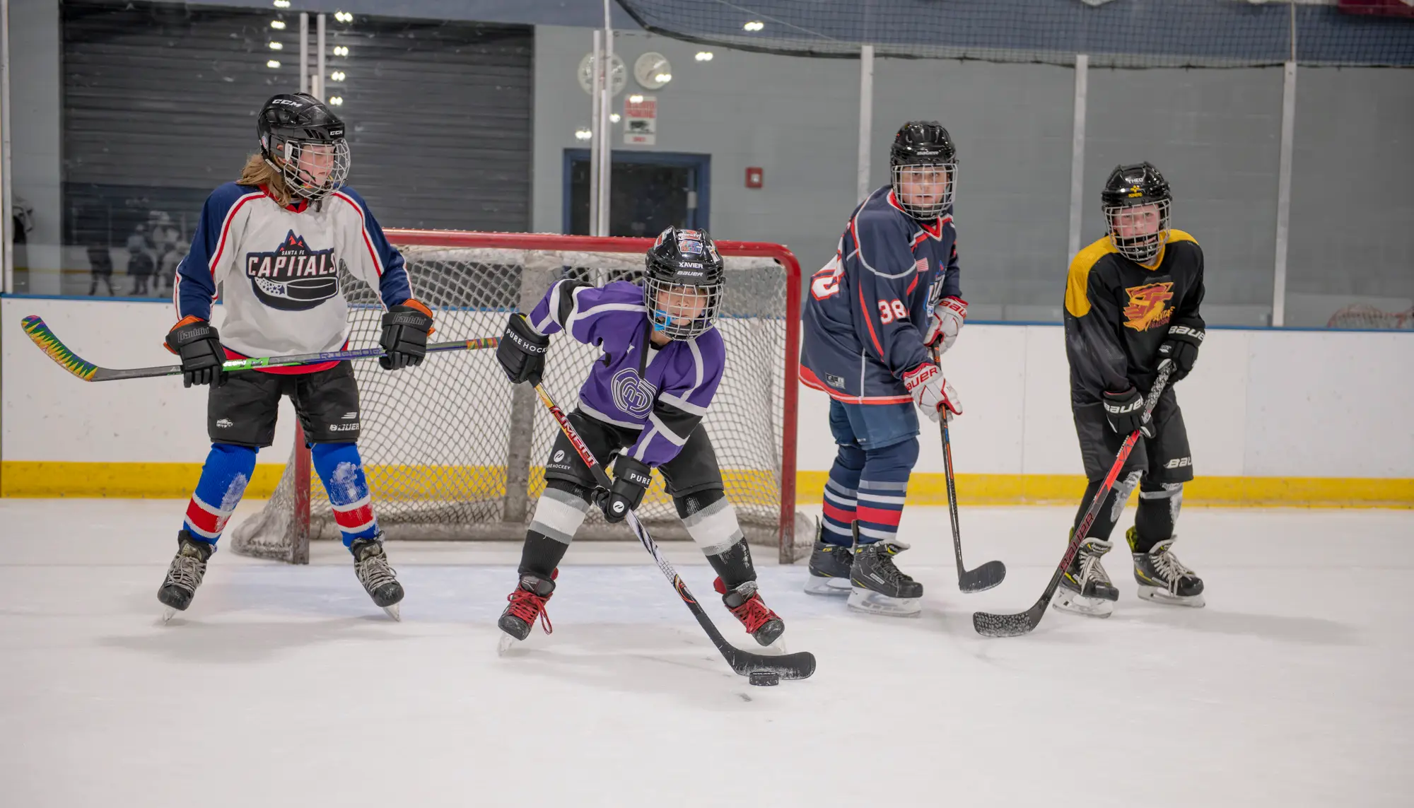 Four young hockey players from the Santa Fe Hockey Association
practice on the ice at the Genoveva Chavez Community Center.